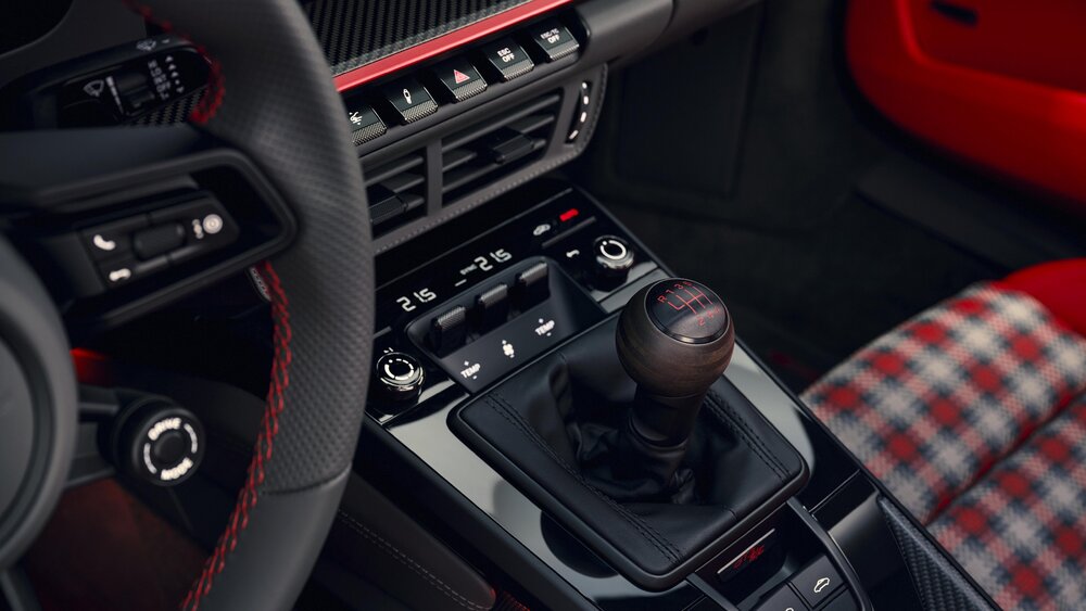 Interior detail showing the six-speed manual shifter with wooden knob and plaid seat upholstery